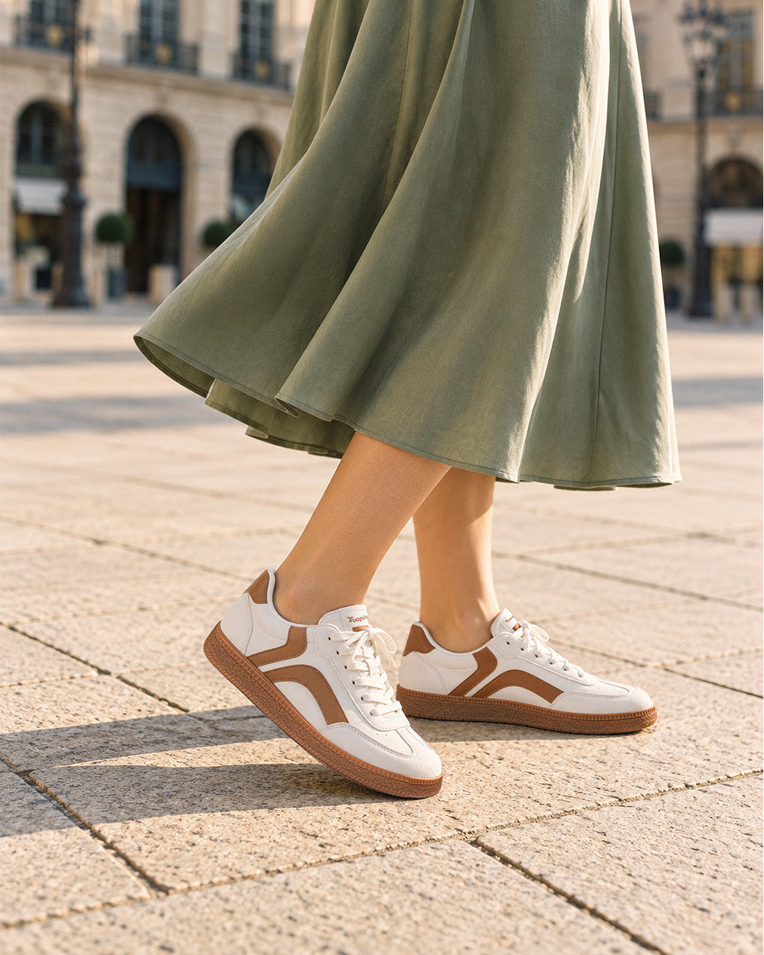 White and brown Tuopin sneakers paired with a flowing green skirt.