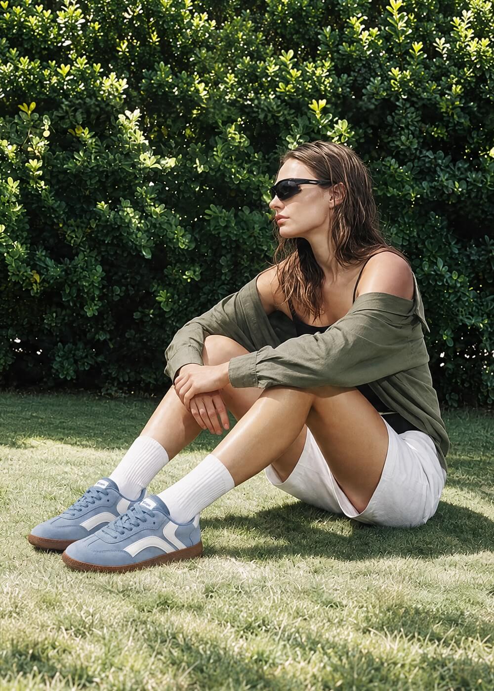 Person seated on grass wearing blue and white Tuopin sneakers and white shorts.