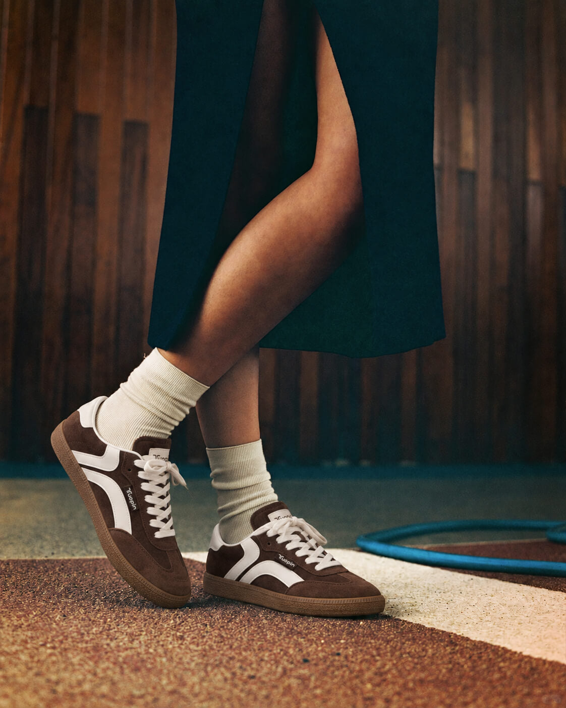 Brown and white Tuopin sneakers worn with white socks and a dark skirt on steps.