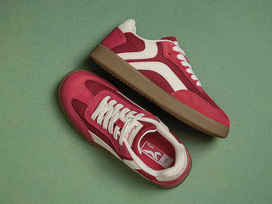 Pair of red Tuopin sneakers on a green background