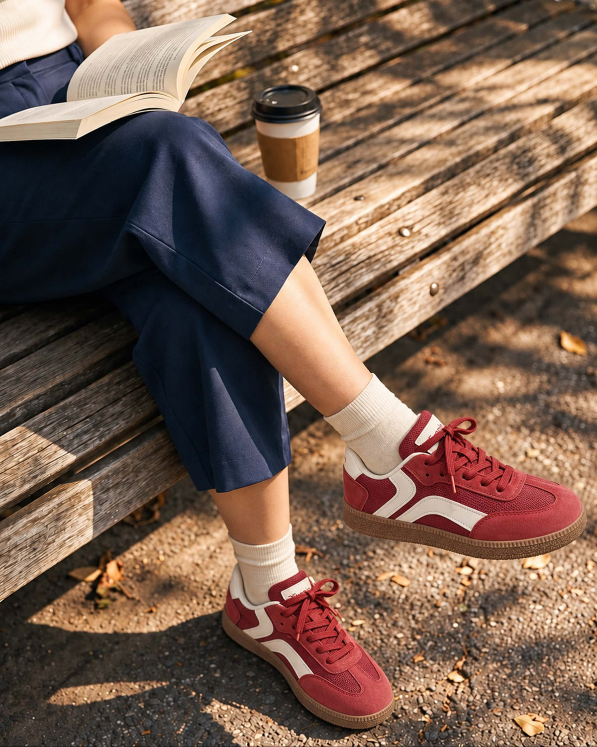 Red Tuopin sneakers with white side stripes, worn with navy trousers while seated on a wooden bench.